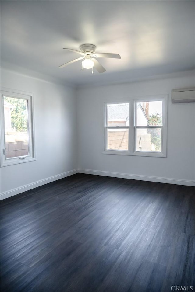 unfurnished room featuring a wall unit AC, ceiling fan, baseboards, and dark wood-type flooring