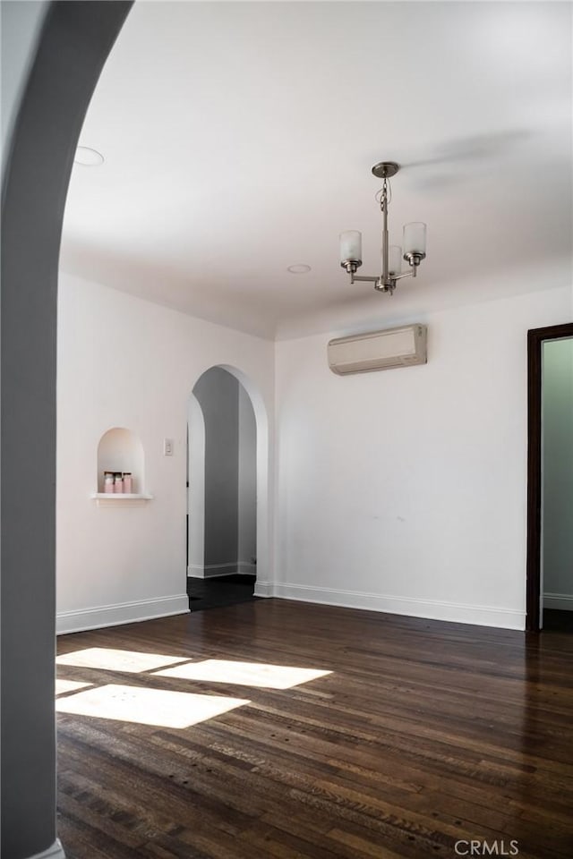 spare room with dark wood-style floors, baseboards, arched walkways, and a wall mounted AC