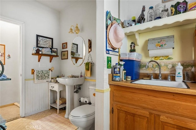 bathroom featuring toilet, wood walls, and sink