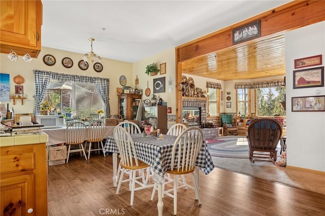 dining area featuring a fireplace, wood-type flooring, and a notable chandelier