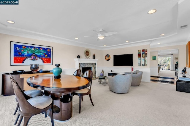 carpeted dining area with ceiling fan, ornamental molding, and a fireplace