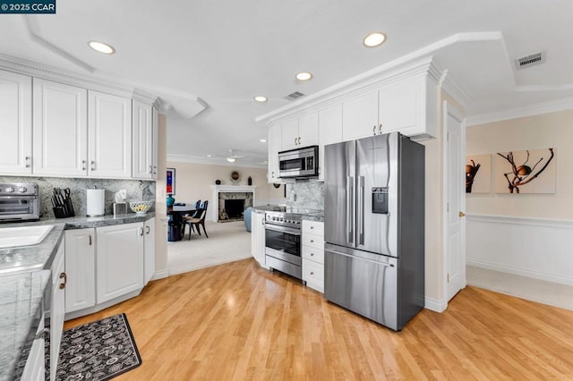 kitchen featuring tasteful backsplash, white cabinetry, stainless steel appliances, and ornamental molding