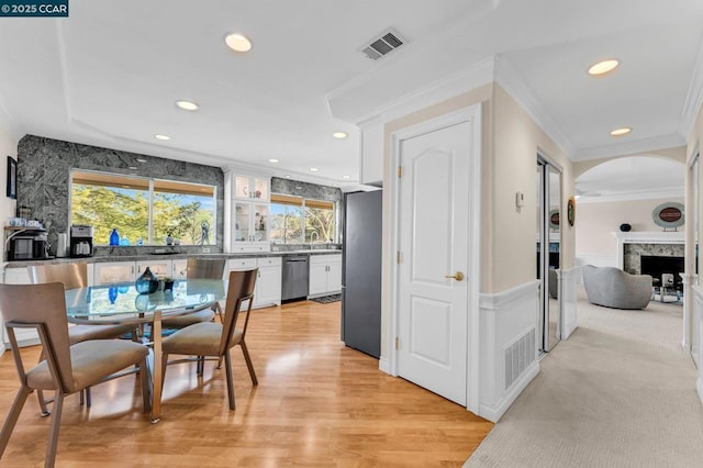 dining room featuring sink, a high end fireplace, ornamental molding, and light wood-type flooring