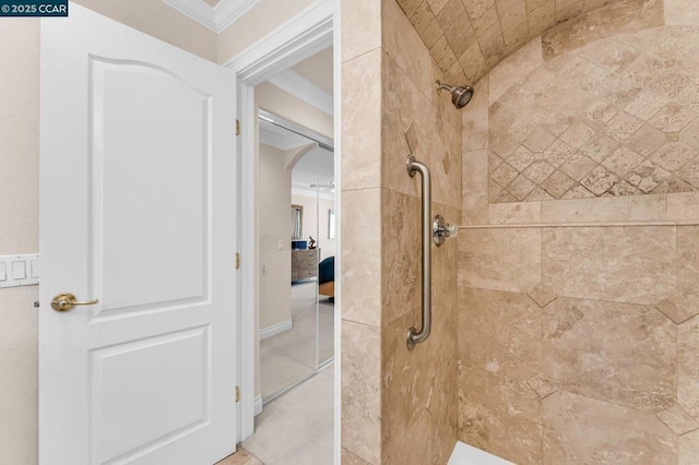 bathroom with tiled shower and crown molding