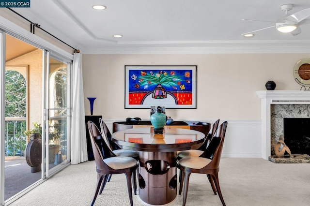 dining area with carpet flooring, ceiling fan, crown molding, and a high end fireplace