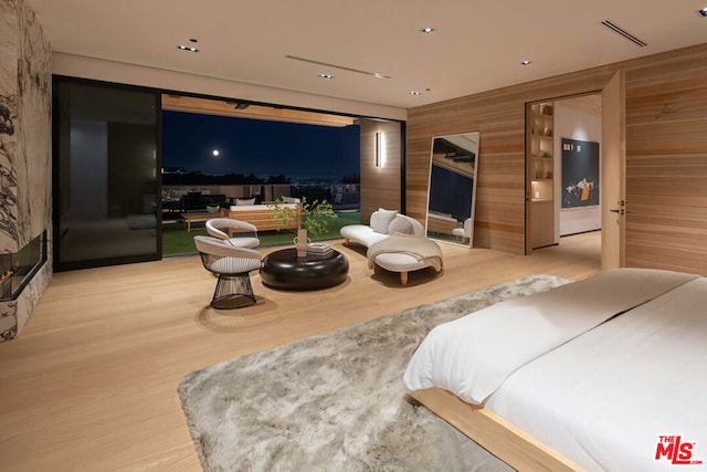 bedroom featuring light wood-type flooring, golf simulator, and wood walls