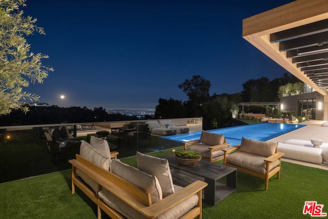 pool at night featuring outdoor lounge area