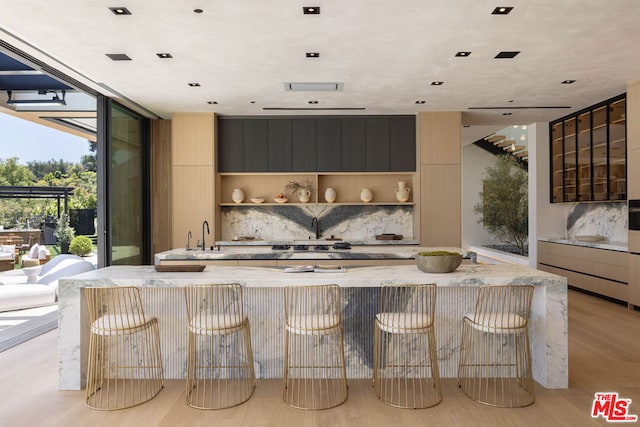 kitchen featuring light hardwood / wood-style floors, gas stovetop, a wall of windows, and backsplash