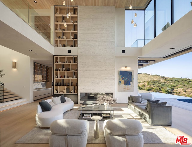 living room featuring a towering ceiling, light hardwood / wood-style floors, a healthy amount of sunlight, and wood ceiling