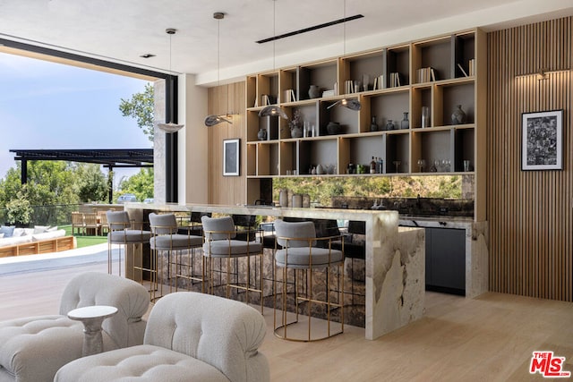 bar featuring light wood-type flooring, decorative light fixtures, and floor to ceiling windows