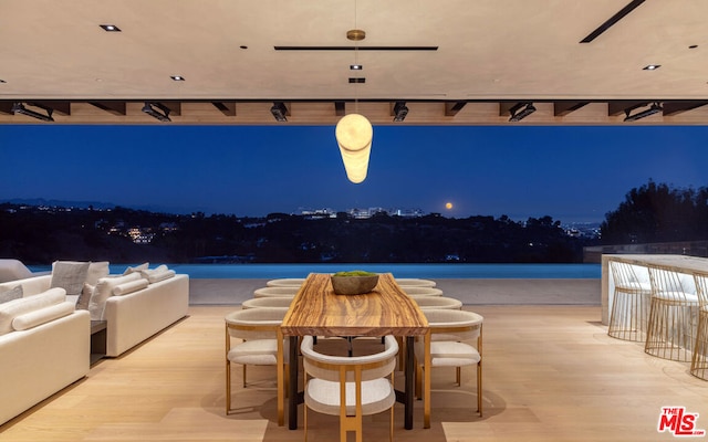 pool at night featuring outdoor lounge area and a water view