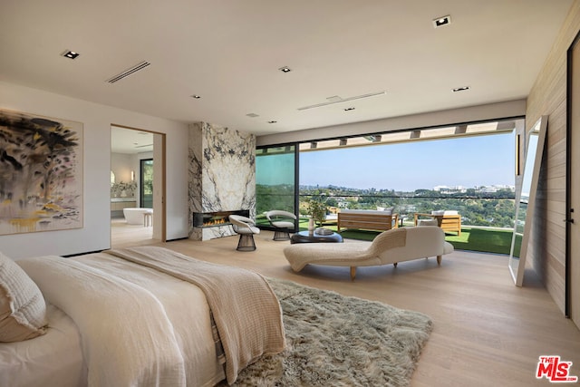 bedroom with ensuite bath and light hardwood / wood-style flooring