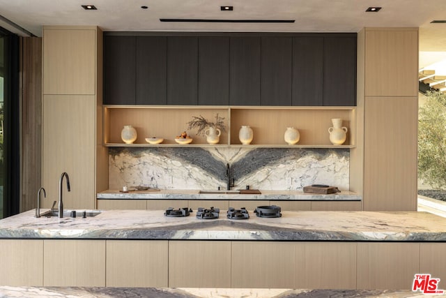 kitchen with light stone counters, sink, and light brown cabinetry