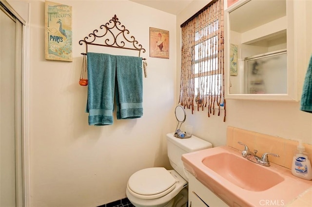 bathroom with vanity, toilet, and a shower with door