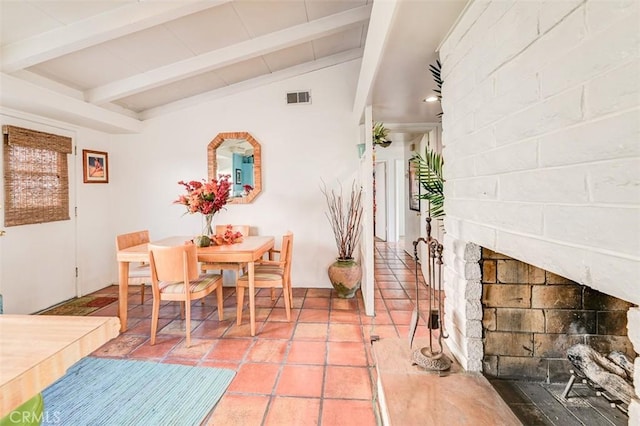 dining space with vaulted ceiling with beams and a fireplace