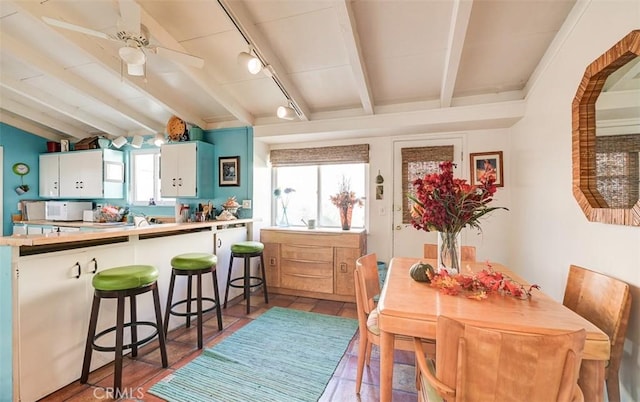 tiled dining room with ceiling fan, beamed ceiling, and rail lighting