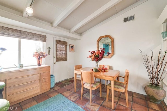 dining area featuring vaulted ceiling with beams and dark tile patterned floors