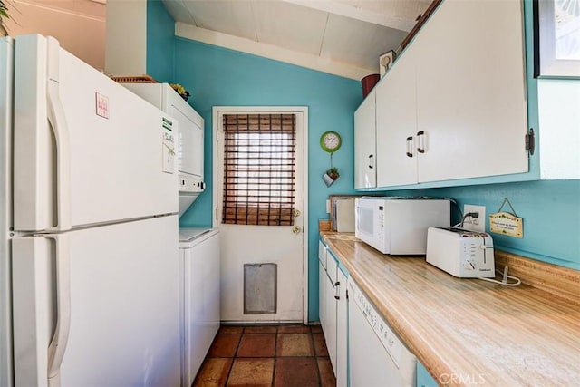 kitchen featuring stacked washer and clothes dryer, white appliances, white cabinetry, and lofted ceiling