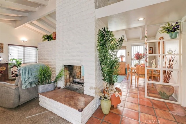 tiled living room featuring vaulted ceiling with beams and a brick fireplace