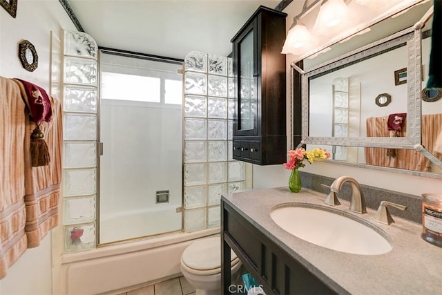 full bathroom featuring tile patterned flooring, toilet, combined bath / shower with glass door, and vanity