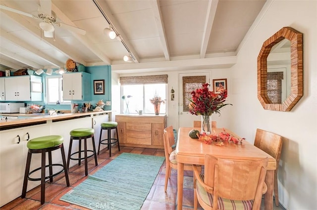 dining room with beamed ceiling, tile patterned flooring, and track lighting