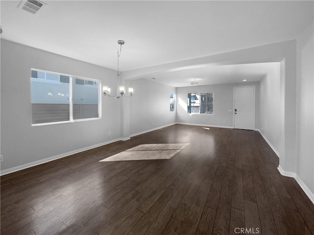 empty room featuring an inviting chandelier and dark hardwood / wood-style floors