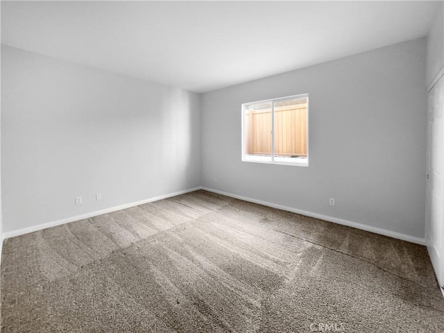 unfurnished room with baseboards and carpet