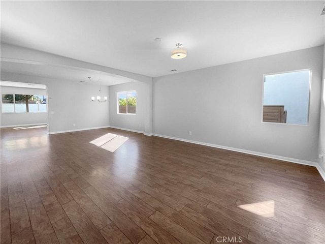 spare room with an inviting chandelier and dark wood-type flooring