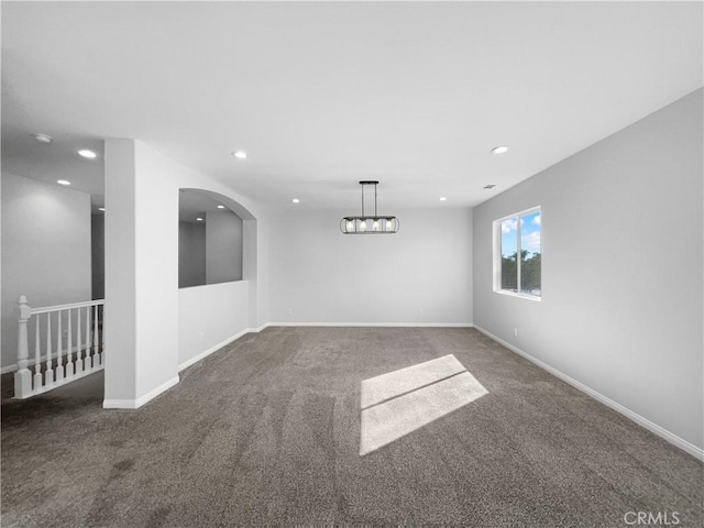 carpeted empty room featuring baseboards, arched walkways, and recessed lighting