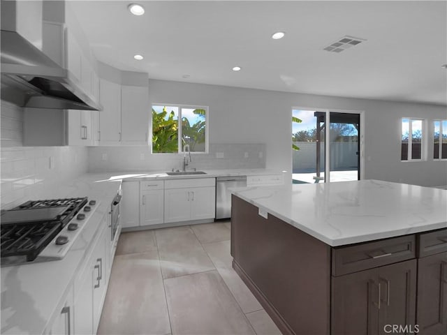 kitchen with white cabinetry, sink, stainless steel appliances, plenty of natural light, and wall chimney exhaust hood