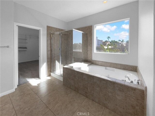 bathroom with a stall shower, tile patterned flooring, a spacious closet, and a garden tub