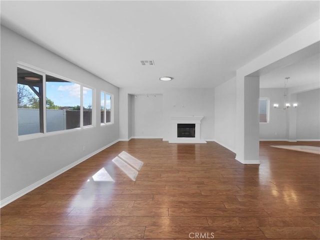 unfurnished living room with dark wood-type flooring and a notable chandelier