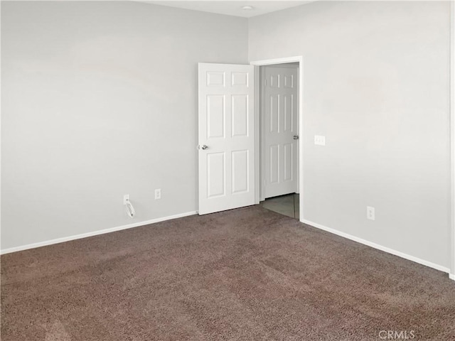 empty room with dark carpet and baseboards