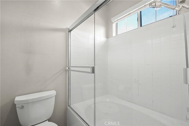 bathroom with combined bath / shower with glass door and toilet