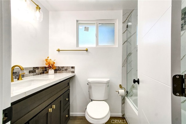 full bathroom featuring decorative backsplash, combined bath / shower with glass door, vanity, hardwood / wood-style flooring, and toilet