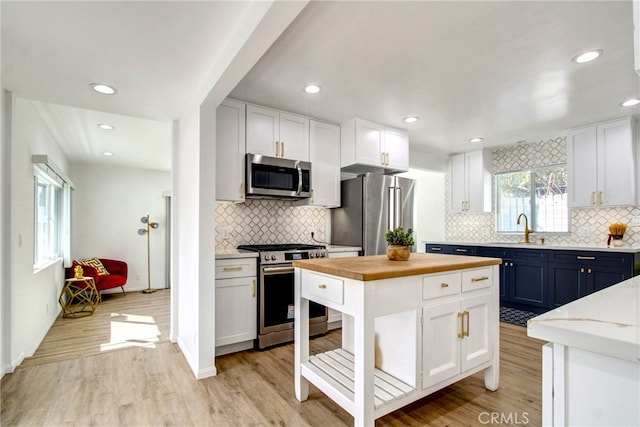 kitchen featuring blue cabinetry, a center island, light hardwood / wood-style flooring, white cabinets, and appliances with stainless steel finishes