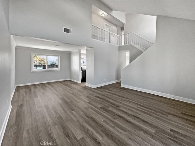 unfurnished living room with a towering ceiling and dark wood-type flooring