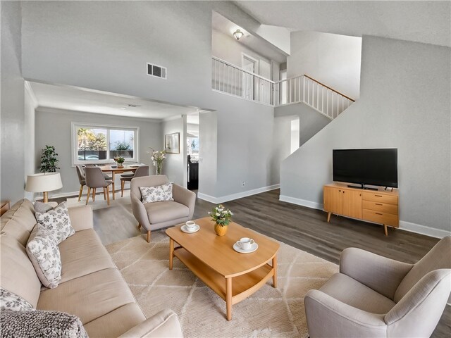 living room with crown molding, a high ceiling, and hardwood / wood-style flooring