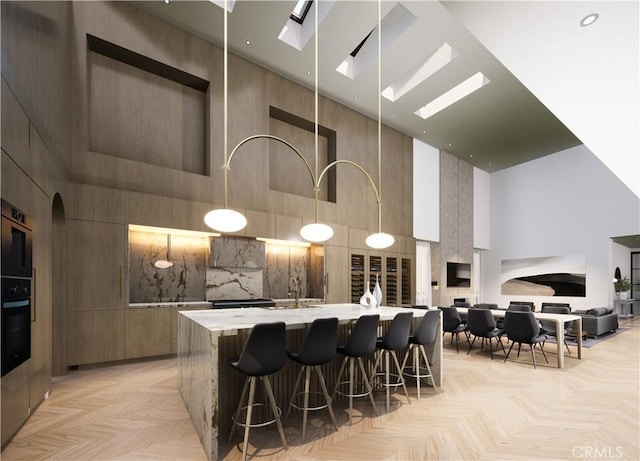 kitchen with light parquet floors, oven, a breakfast bar area, and a towering ceiling