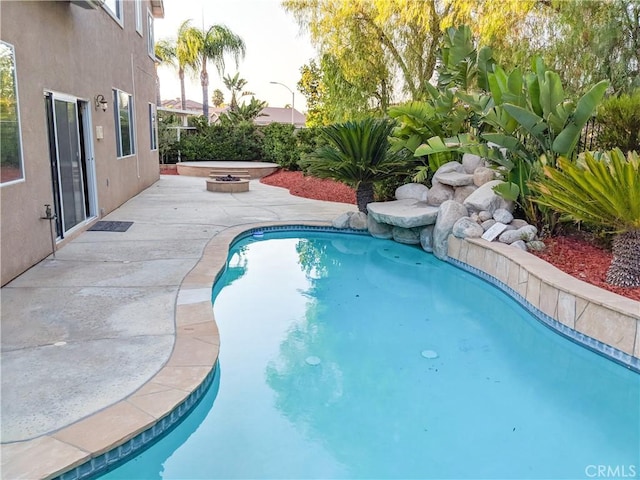 view of swimming pool with a patio and a fire pit