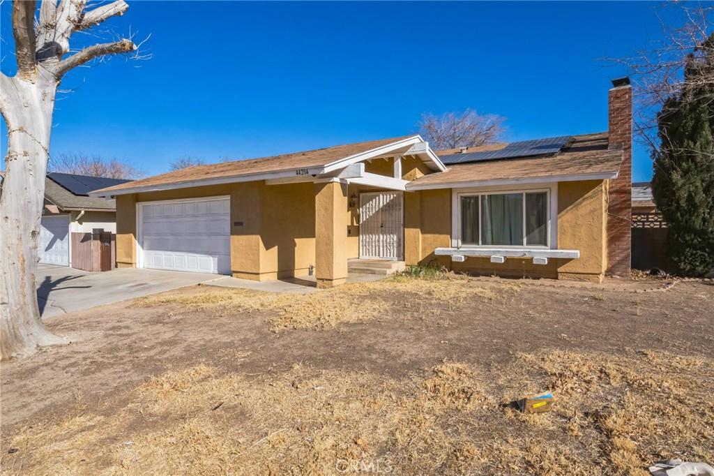 ranch-style house with solar panels and a garage