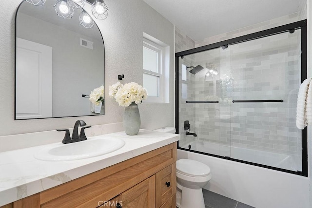 full bathroom featuring combined bath / shower with glass door, vanity, and toilet