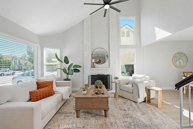 living room featuring ceiling fan, plenty of natural light, light hardwood / wood-style flooring, and a brick fireplace