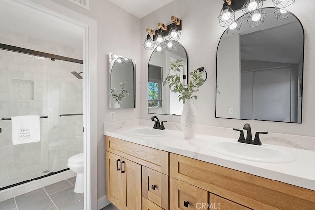 bathroom with tile patterned floors, a shower with door, vanity, and toilet