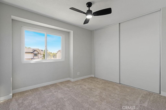 unfurnished bedroom with ceiling fan, light carpet, and a closet