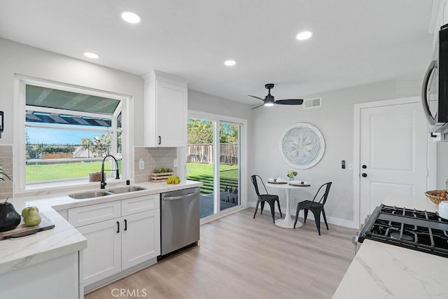 kitchen with dishwasher, white cabinets, sink, ceiling fan, and tasteful backsplash