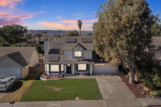 view of front of property featuring a mountain view, solar panels, a garage, and a lawn