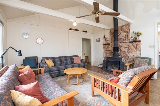 living room featuring ceiling fan, beam ceiling, a wood stove, and high vaulted ceiling