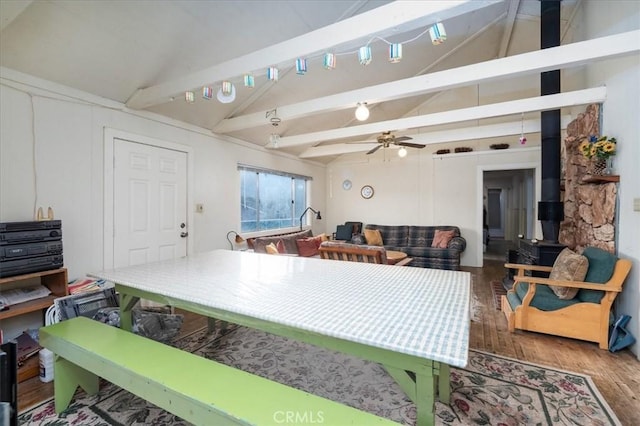 kitchen featuring hardwood / wood-style floors, vaulted ceiling with beams, a wood stove, and ceiling fan