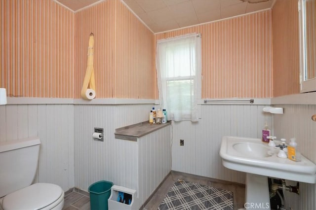 bathroom featuring wood walls, toilet, and crown molding